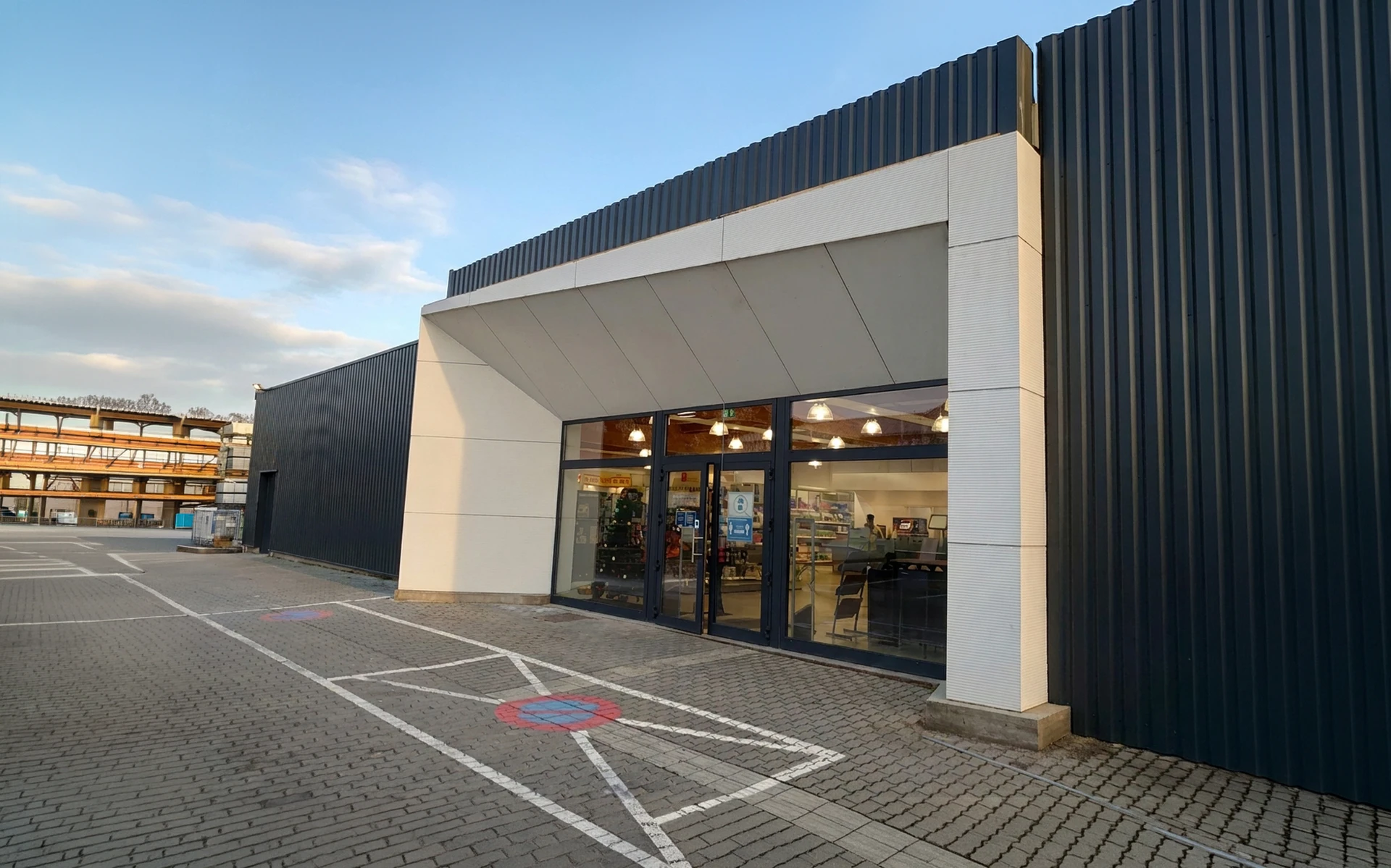 Entrée d'un commerce de détail, façade extérieure moderne avec bardage métallique noir et panneaux blancs