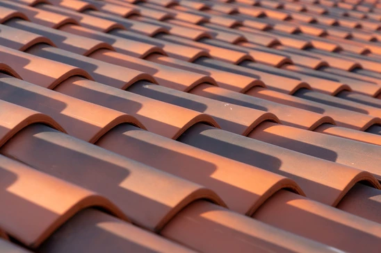 Ouvrier installant des tuiles en terre cuite rouge sur une toiture en construction